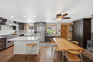 Two tone kitchen with light stone counters, stainless steel appliances, dual tone cabinets, dark wood-style floors, and a kitchen island