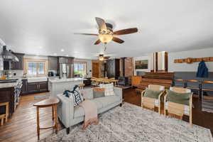 Living room with a wood stove, dark wood finished floors, recessed lighting, and a ceiling fan