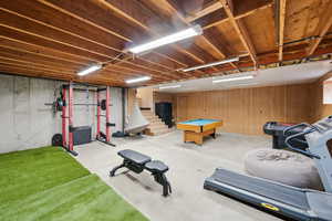 Workout area with concrete floors, pool table, and wood walls