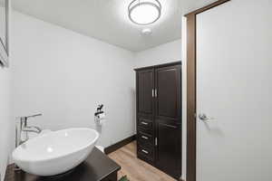Bathroom featuring light wood finished floors, a textured ceiling, and vanity