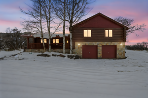 View of front of home with an attached garage, a porch, and stone siding