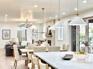 Dining space with light wood-type flooring, a stone fireplace, and recessed lighting