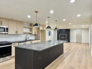Kitchen with stainless steel appliances, light wood finish cabinetry, light wood-style flooring, and tasteful backsplash