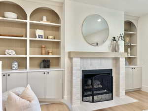 Living area featuring built in features, light wood-style floors, and a tile fireplace