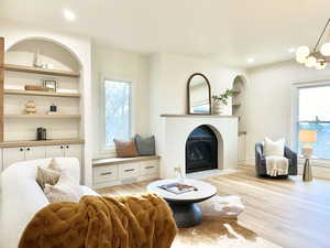 Master bedroom featuring light wood-style flooring, built in shelves, a fireplace with flush hearth, and suspended lighting