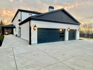 Property exterior at dusk with concrete driveway, an attached garage, and brick siding