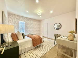 Bedroom featuring light wood finished floors, a textured ceiling, wallpapered walls, and recessed lighting