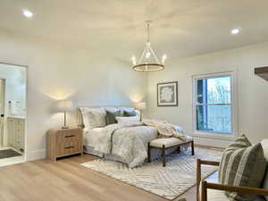 Main floor Master featuring light wood-style floors, suspended lighting, ensuite bath, and a textured ceiling