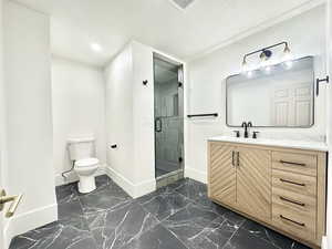 Bathroom with vanity, a shower stall, dark marble finish flooring, a textured ceiling, and recessed lighting