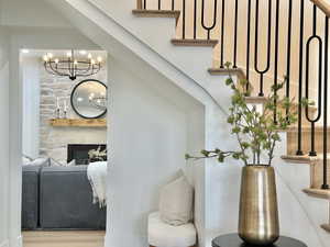 Stairs featuring hanging lights, a stone fireplace, and wood finished floors