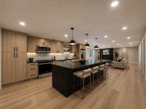 Virtually staged -- Kitchen with a spacious island, open floor plan, stainless steel appliances, light wood-style flooring, and a breakfast bar