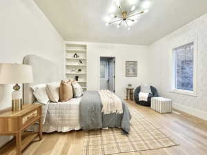 Bedroom featuring light wood finished floors, suspended lighting, and a textured ceiling