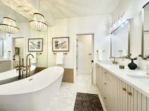 Main floor Master bathroom featuring double vanity, a soaking tub, light marble finish flooring, and suspended lighting