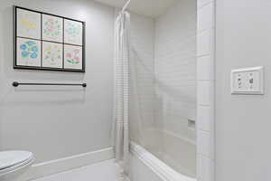 Full bathroom featuring shower / bath combination with curtain and light tile patterned floors