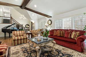 Living room with wood finished floors, hanging lights, and lofted ceiling with beams