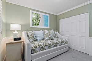 Bedroom featuring crown molding, carpet, a closet, and a textured ceiling