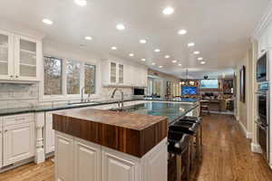 Kitchen with backsplash, a kitchen breakfast bar, open floor plan, and white cabinetry