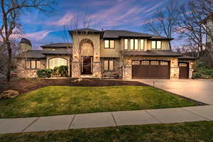 View of front of property featuring stone siding, stucco siding, driveway, an attached garage, and a lawn