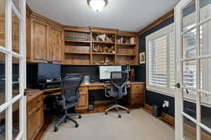 Home office with french doors, light wood finished floors, a textured ceiling, and crown molding