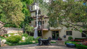 Rear view of property with a balcony, stucco siding, french doors, a patio, and a chimney