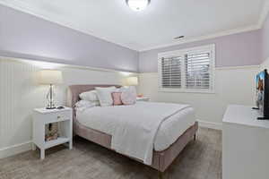 Carpeted bedroom with crown molding and a wainscoted wall