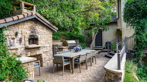 View of patio / terrace featuring a fireplace and an outdoor kitchen / dining area