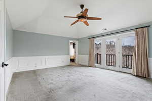 Unfurnished bedroom featuring a wainscoted wall, carpet floors, a decorative wall, access to outside, and a ceiling fan
