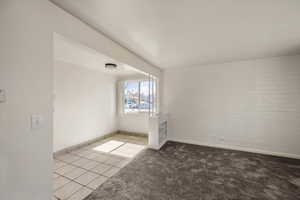 Carpeted spare room featuring tile patterned flooring and baseboards