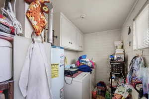 Laundry room featuring cabinet space, gas water heater, crown molding, and separate washer and dryer