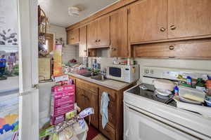 Kitchen with white appliances, light countertops, and wood finish cabinetry