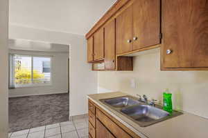 Kitchen with wood finish cabinets, light countertops, light carpet, and light tile patterned floors