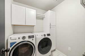 Laundry room with cabinet space, washer and clothes dryer, and light tile patterned floors