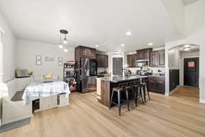 Kitchen with stainless steel appliances, dark wood finish cabinetry, a breakfast bar area, an island with sink, and arched walkways