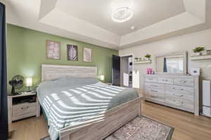 Bedroom featuring light wood-style floors and a raised ceiling