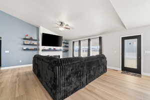 Living area with light wood-style flooring, a ceiling fan, lofted ceiling, and a fireplace