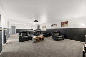 Cinema room with a wainscoted wall, carpet, and wood walls