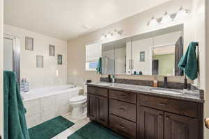 Bathroom featuring double vanity, a stall shower, a bath, and light tile patterned floors