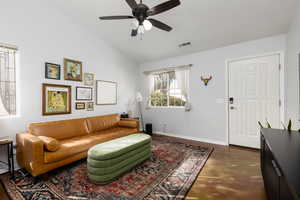 Living area with lofted ceiling, concrete floors, and ceiling fan