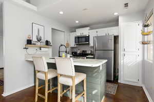 Kitchen with stainless steel appliances, white cabinets, decorative backsplash, a peninsula, and recessed lighting