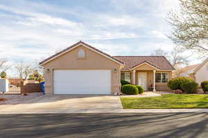 View of front facade featuring a tiled roof, stucco siding, concrete driveway, and an attached garage