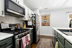 Two tone kitchen featuring stainless steel appliances, light countertops, concrete floors, recessed lighting, and tasteful backsplash