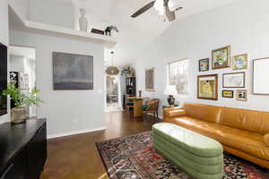 Living area with finished concrete flooring, a ceiling fan, and vaulted ceiling