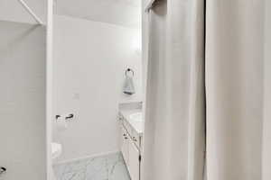 Full bath with vanity, light marble finish floors, and curtained shower/ bathtub
