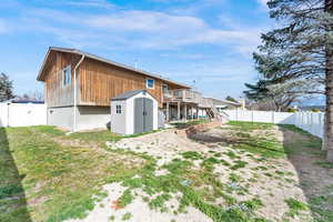 Back of property featuring a storage shed, a fenced backyard, a gate, and a wooden deck
