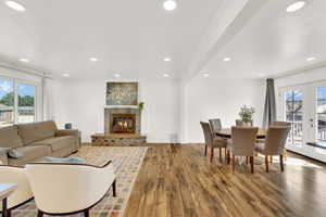 Living area with healthy amount of natural light, finished floors, french doors, recessed lighting, and a brick fireplace