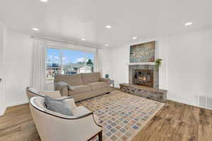Living area featuring finished floors, a brick fireplace, and recessed lighting
