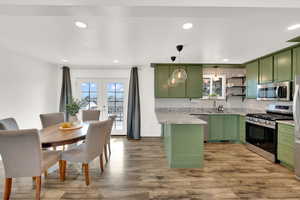 Kitchen with green cabinetry, stainless steel appliances, french doors, light wood-style flooring, and granite countertops