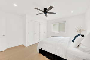 Bedroom featuring new hardwood flooring, two closets, a ceiling fan, and recessed lighting