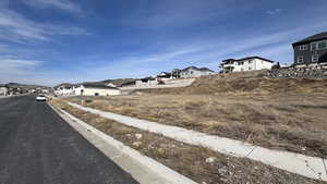 View of asphalt street with a residential view, curbs, and sidewalks