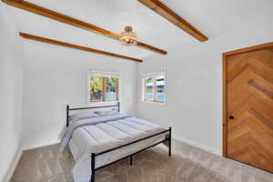 Bedroom with beam ceiling and light carpet
